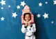child dressed in as an astronaut standing in front of a blue background with stars