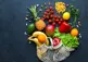 bag of colourful fruit and vegetables spilled out on a black background.