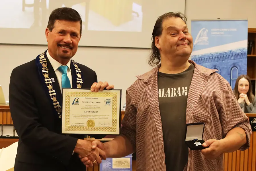 Photo of a man with brown hair accepting certificate from another man with brown hair.