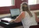 Person sitting at a table with a computer and book.