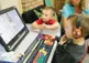 Two children sitting around a computer. 